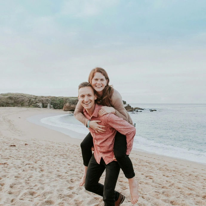 man carrying woman beside seashore